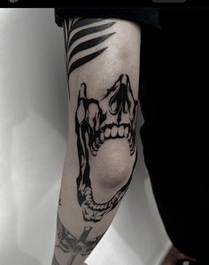 a man's arm with a skull and cross tattoo on the left side of his leg