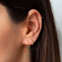 a woman wearing gold ear cuffs with three small diamonds on the end of her ear