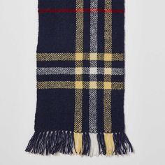 the classic check cash scarf in navy and yellow is shown with fringes on it