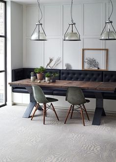 a dining room table with two chairs and a bench in front of it, surrounded by white paneling