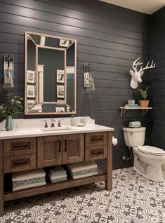 a bathroom with a sink, toilet and deer head on the wall above it's mirror