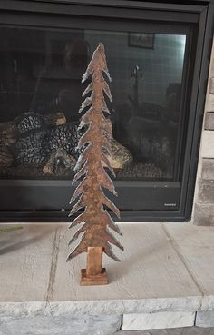 a small wooden christmas tree sitting in front of a fireplace