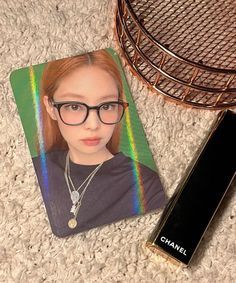 a close up of a person wearing glasses near a cell phone and a pen on the ground