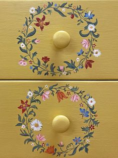 two painted drawers with flowers and leaves on the front, one has a round handle