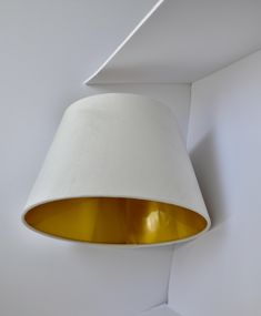 a white lamp hanging from the ceiling with a yellow light on it's side