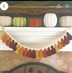 a mantle decorated with pumpkins and tassels for fall decor in a living room