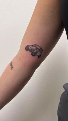 a woman's arm with a small car tattoo on it