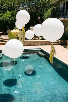 some balloons floating in the air near a swimming pool