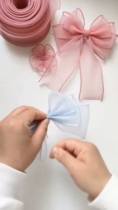 the person is making ribbons with pink and blue bows on them, along with other crafting supplies