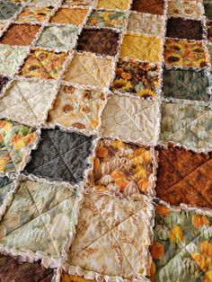 an old quilt is laying on top of a bed with many different colors and patterns