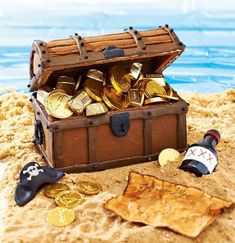 an open trunk filled with gold coins sitting on top of a sandy beach