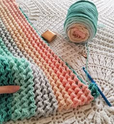 a crocheted blanket with yarn next to it