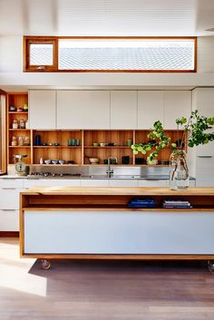 an open kitchen with two stools in front of the counter and shelves on the wall