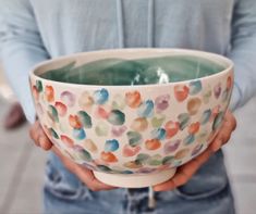 a person holding a colorful bowl in their hands with water coming out of the bottom