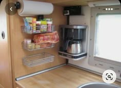 a kitchen area with a sink, coffee maker and shelves on the side of the wall