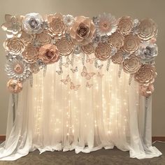 the backdrop is made out of paper flowers and butterflies, with white drapes on either side