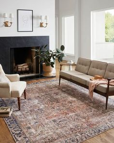 a living room filled with furniture and a rug on top of a hard wood floor