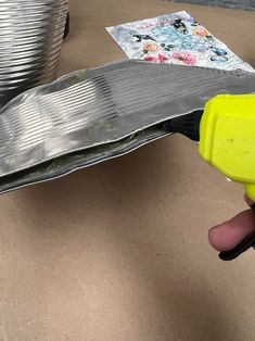 a person holding a yellow blow dryer in front of some tin foil on a table