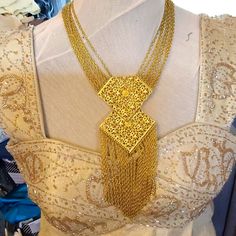 a woman wearing a gold necklace with chains attached to the back of her neck and on top of a mannequin