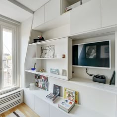 a living room filled with furniture and a flat screen tv on top of a white shelf