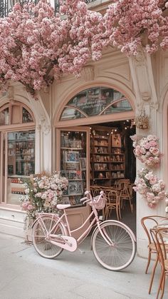 a pink bicycle parked in front of a store with flowers on the windows and doors