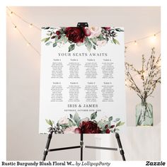 a seating chart with burgundy flowers and greenery is displayed in front of a white backdrop