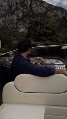 a man driving a boat with mountains in the background