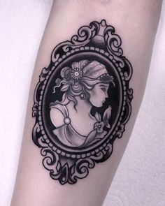 a black and white photo of a woman's face in a frame tattoo on the arm