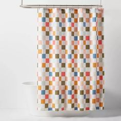 a bathroom with a shower curtain that has different colored squares on it and is next to a toilet