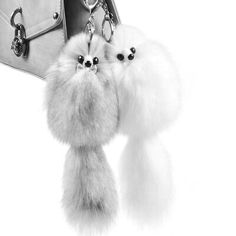 two poodles are hanging from the handle of a handbag on a white background