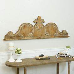 a wooden table topped with two white vases next to a wall mounted shelf filled with books