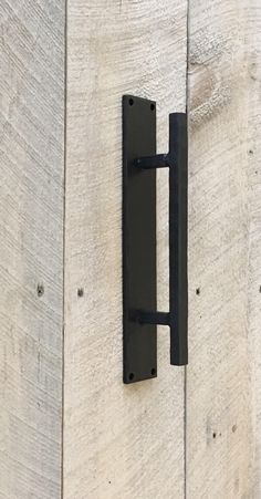 a black door handle on the side of a white wooden building with wood planks