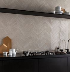 a kitchen with black cabinets and white tile backsplash, coffee pot on the stove