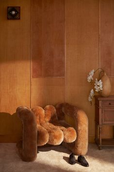 a chair made out of fake fur in front of a wooden wall with flowers on it