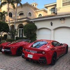 two red sports cars parked next to each other in front of a large house with palm trees