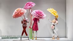 three mannequins holding umbrellas in front of a white wall