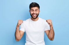 a man in white shirt posing with his fist up and looking at the camera on blue background