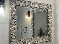 a bathroom mirror that has shells on the wall and lights above it, along with other items