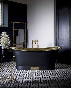 a black and gold bathtub in a bathroom next to a window with white flowers