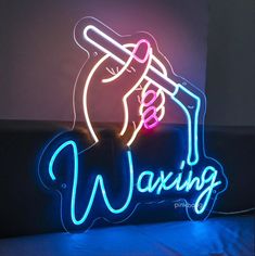 a neon sign that says waxing with a hand holding a toothbrush in it