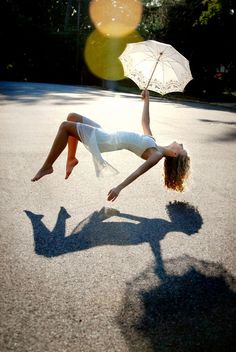 a woman is upside down on the ground holding an umbrella and posing for a photo