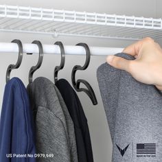 a person's hand is hanging clothes from a rack on a white coat hanger