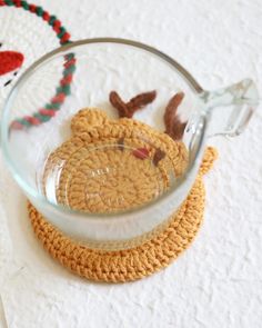 a glass bowl with some crocheted reindeers in it on a white surface