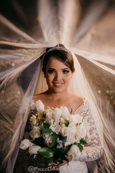 a woman in a wedding dress holding a bouquet of white flowers and wearing a veil