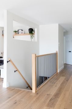 an empty living room with wood floors and white walls, along with wooden railings