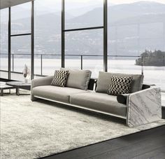 a living room filled with lots of furniture and large windows overlooking the water's edge