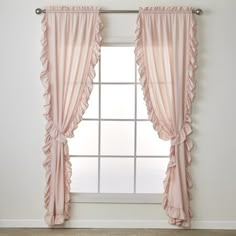 a window with pink ruffled curtains in front of a white wall and wooden floor