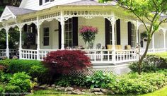 a white house with black shutters and flowers on the porch