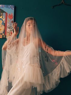 a woman wearing a veil and dress in front of a wall