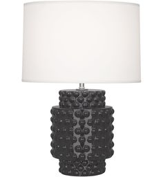 a black table lamp with a white shade on the top and an oval shaped base